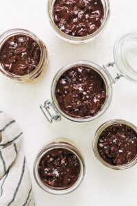 Chocolate pudding in jars on a white table.