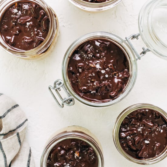 Chocolate pudding in jars on a white table.