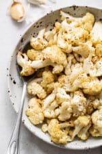 Roasted cauliflower in a bowl with a spoon.