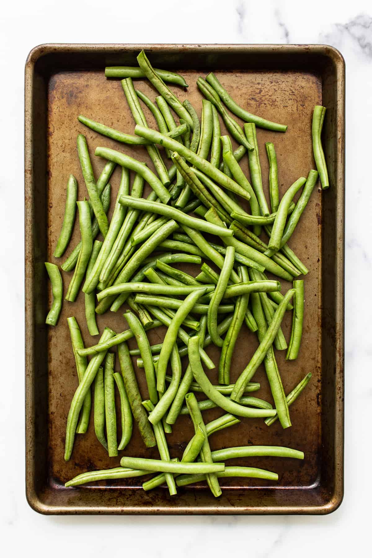 Uncooked green beans on a baking sheet. 