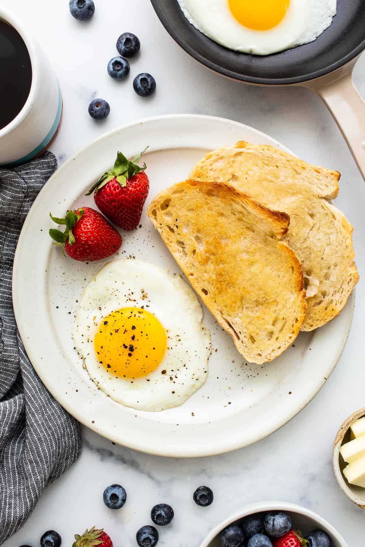 A sunny side up egg on a plate with salt and pepper.
