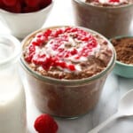 Chocolate raspberry overnight oats with whipped cream and raspberries.