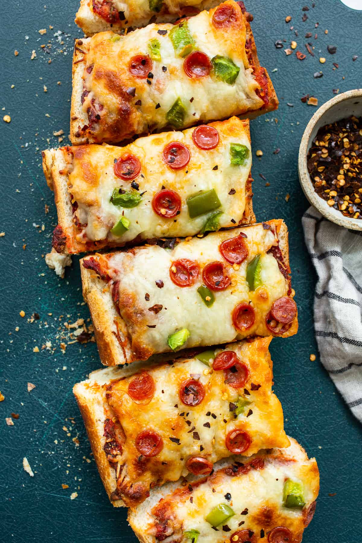 French bread pizza sliced on a cutting board.
