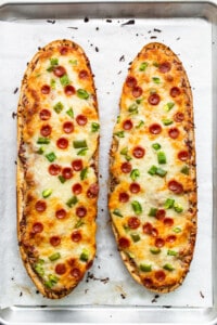 Two slices of pizza bread on a baking sheet.