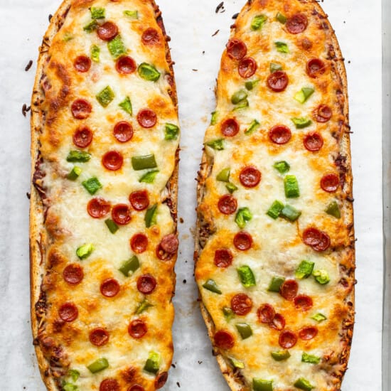 Two slices of pizza bread on a baking sheet.