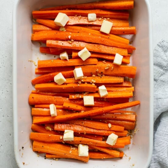Sliced carrots in a white baking dish.
