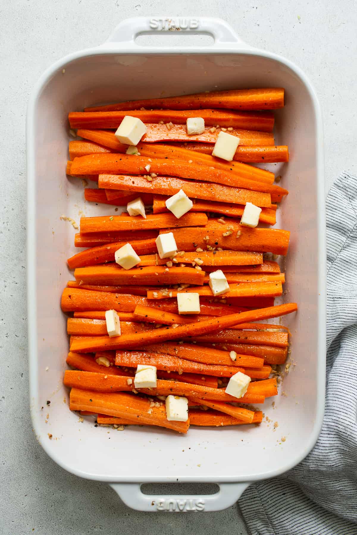 Carrots in a casserole dish topped with butter.
