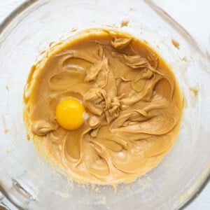 A bowl of peanut butter with an egg in it.