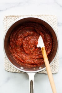 Tomato sauce in a pan with a wooden spoon.