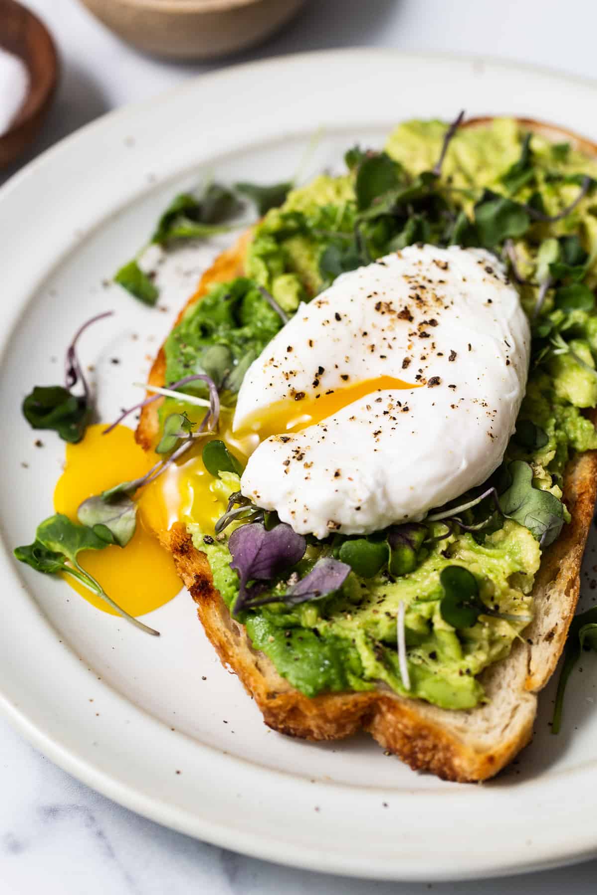 Poached egg with avocado toast on a plate.