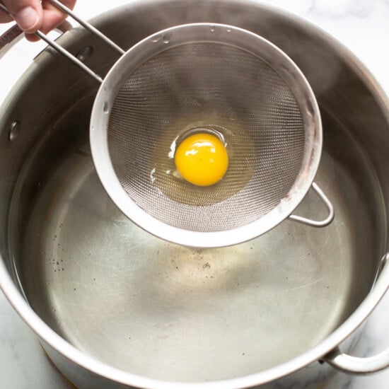 A person is holding an egg in a pan.