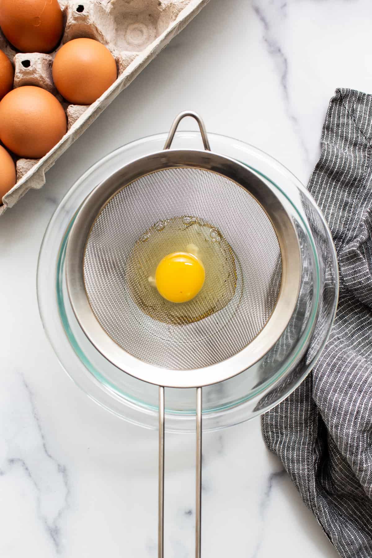 Raw egg in a mesh strainer.