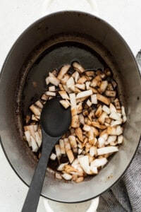 A pot with onions in it and a black spoon.