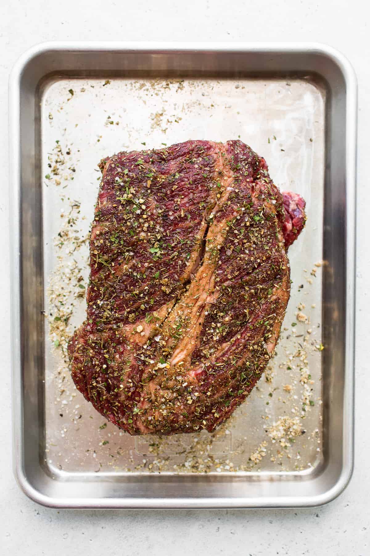 Raw chuck roast on a baking sheet.