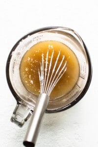 A whisk in a bowl with a liquid in it.