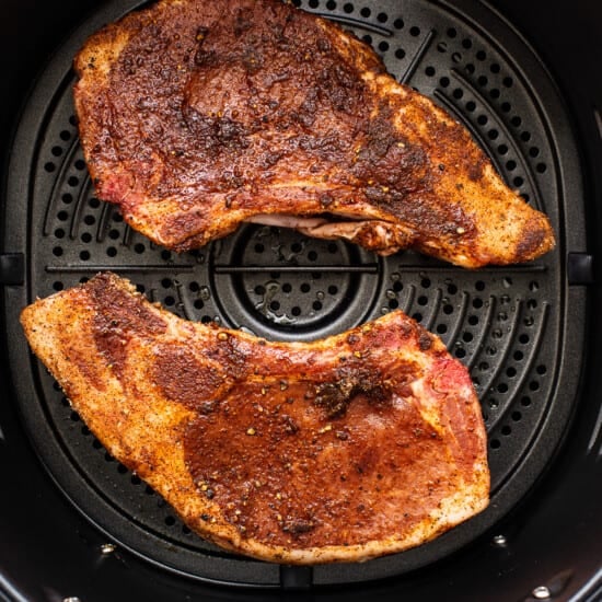 Two pieces of meat in an air fryer.