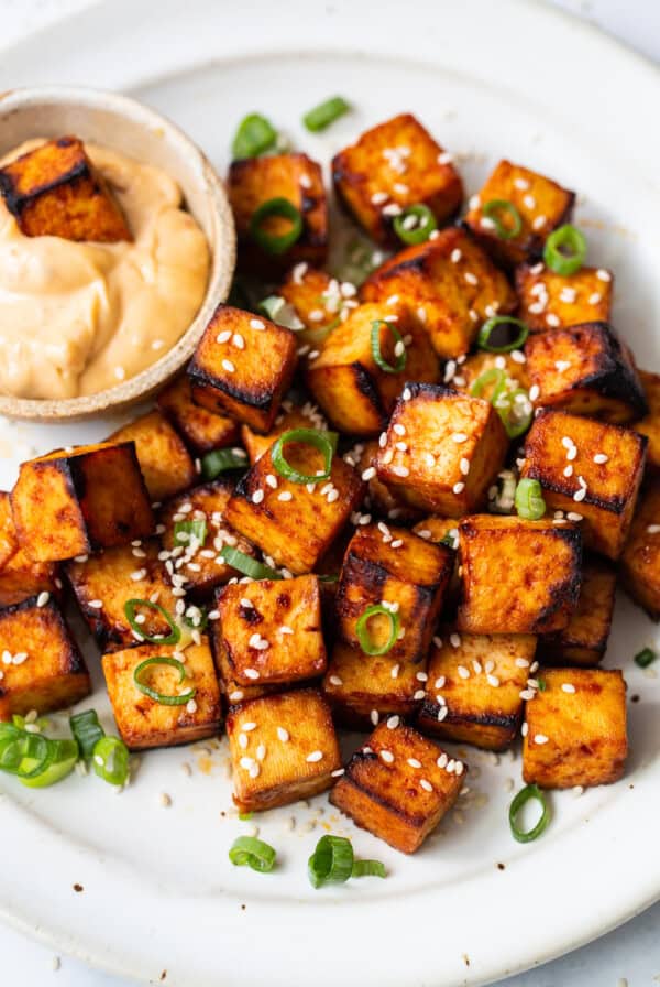 Grilled tofu on a plate with sesame dipping sauce.