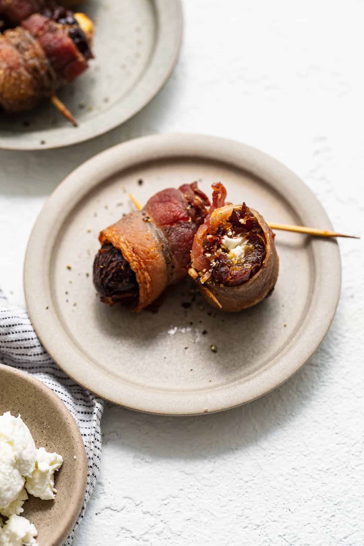 Bacon wrapped dates with goat cheese on a plate.