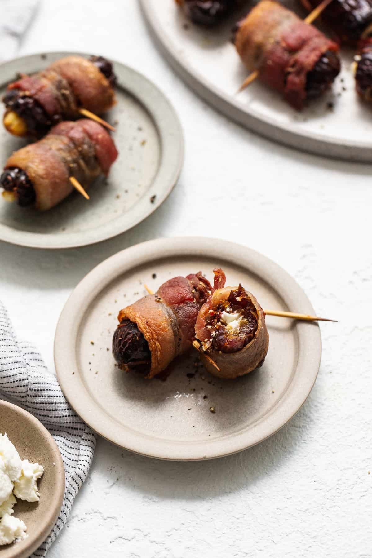 Bacon wrapped dates with goat cheese on a plate.