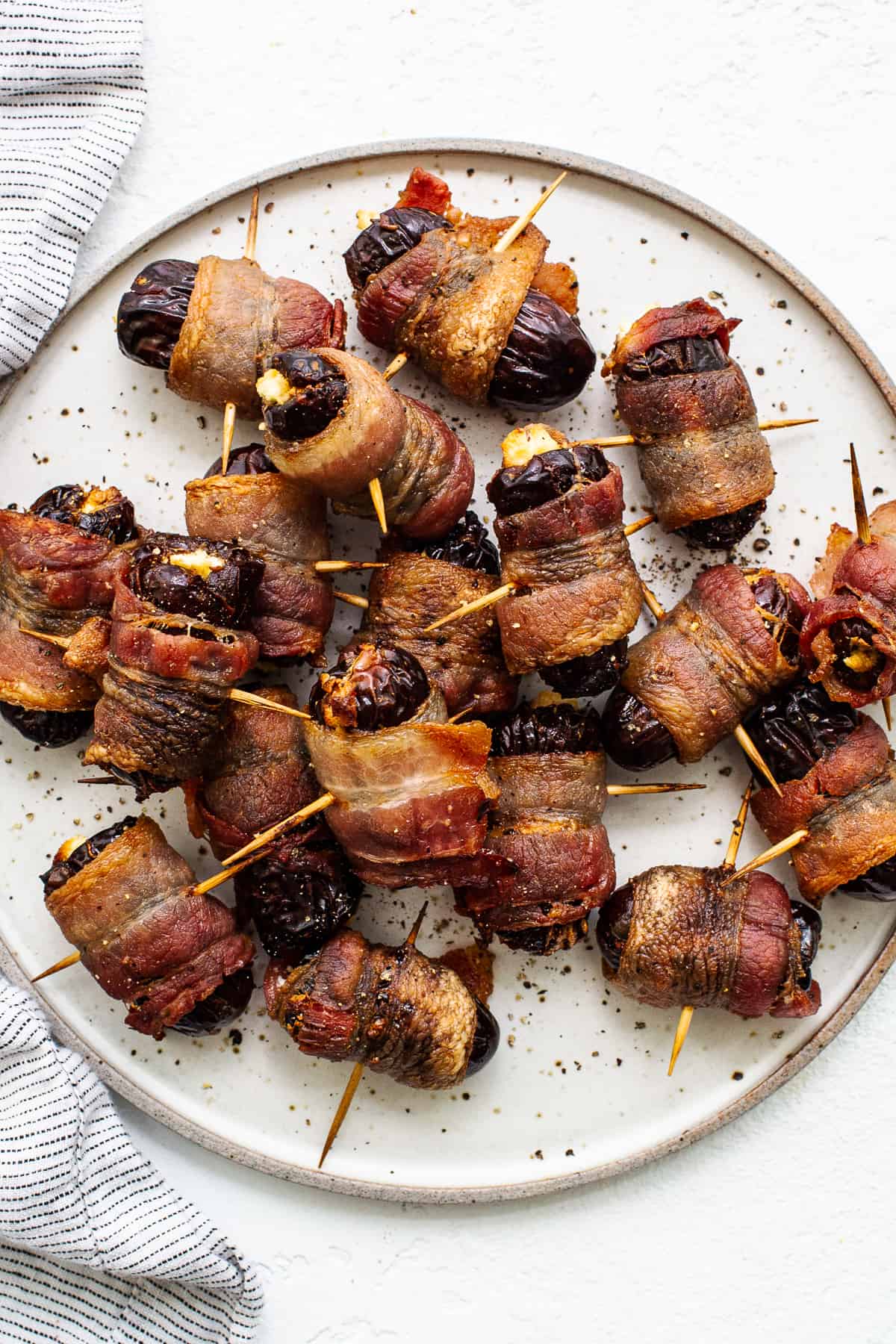 Bacon wrapped dates with goat cheese on a plate.