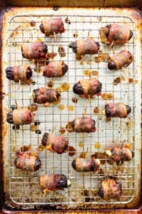 Bacon wrapped dates on a baking sheet.