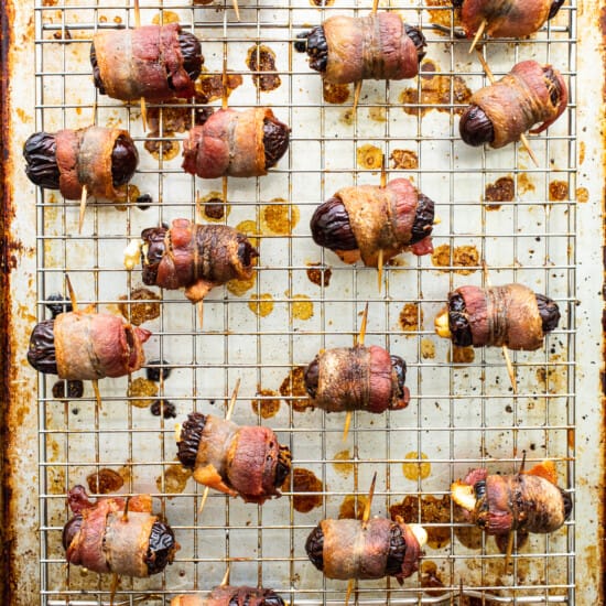 Bacon wrapped dates on a baking sheet.