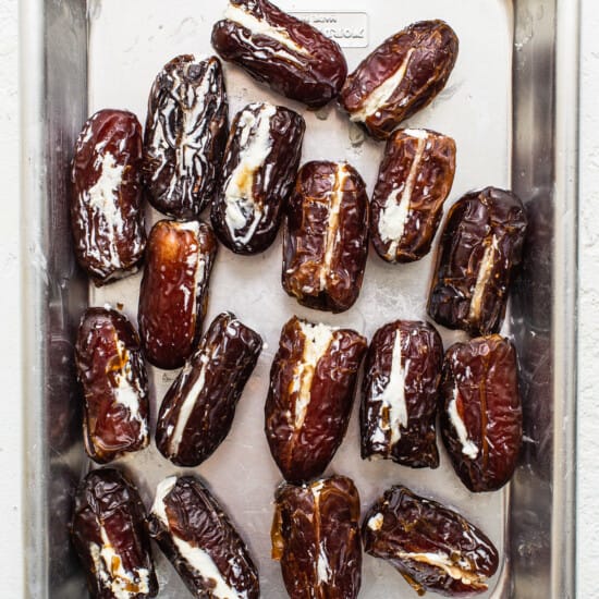 Dates in a metal pan on a white surface.