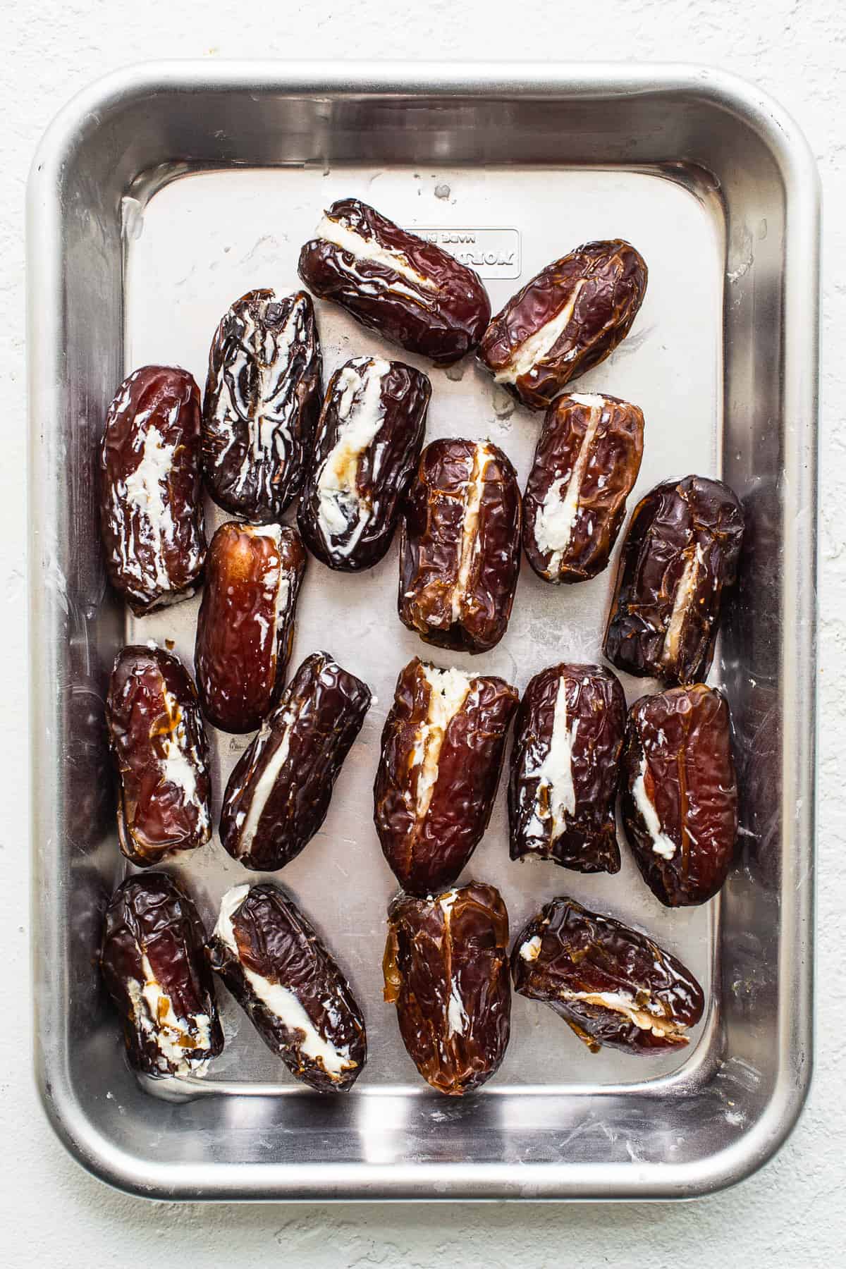 Dates stuffed with goat cheese on a baking sheet.