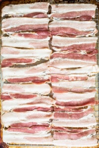 Sliced bacon on a baking sheet.