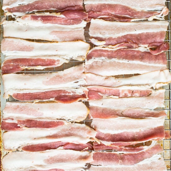 Sliced bacon on a baking sheet.