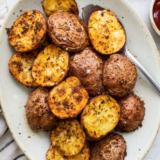 Roasted potatoes on a plate with ketchup.