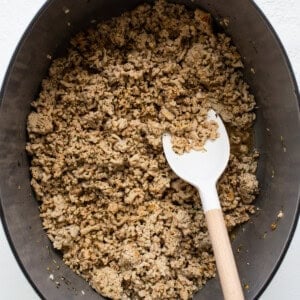 Granola in a pan with a wooden spoon.