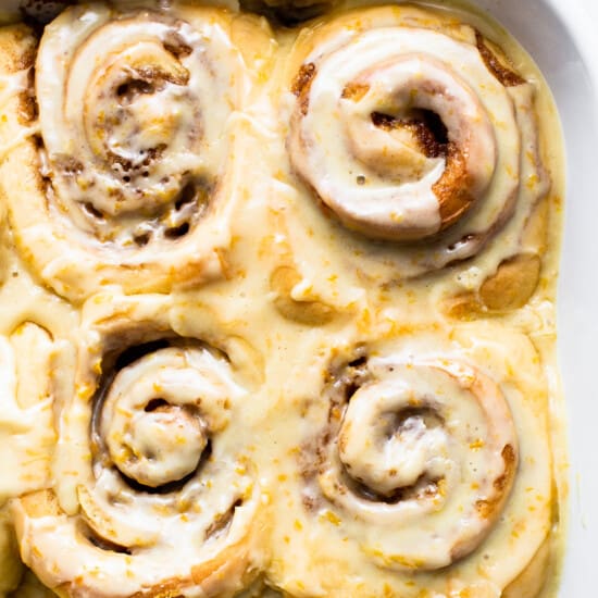 Frosted orange rolls in a casserole dish.