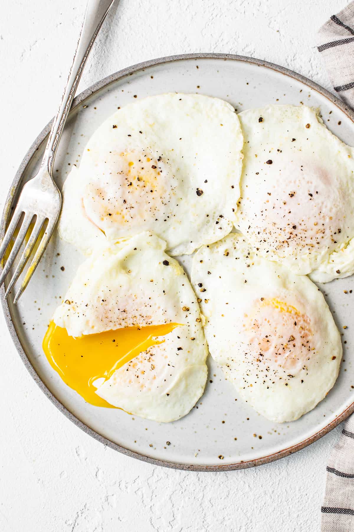Over easy eggs on a plate.