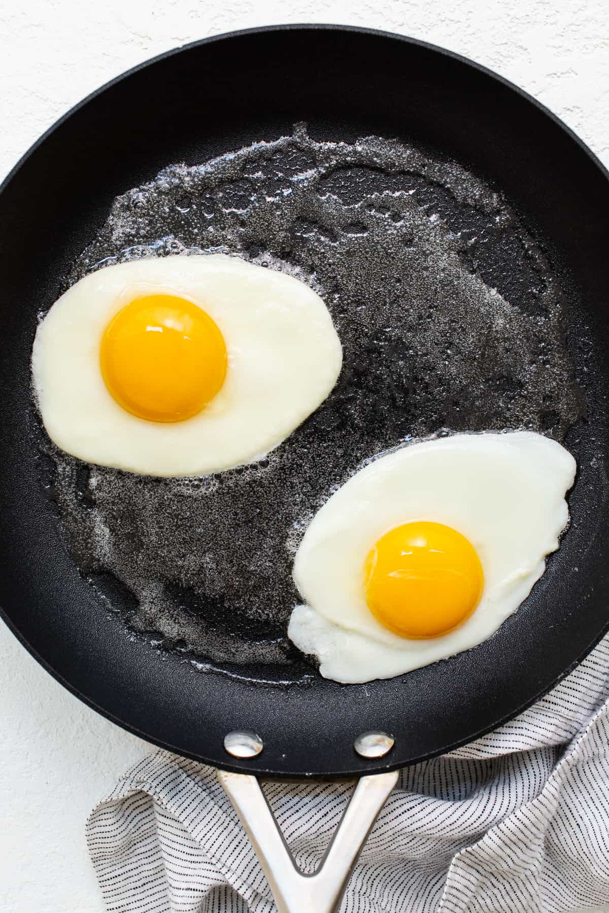 Over hard eggs cooking in a skillet.