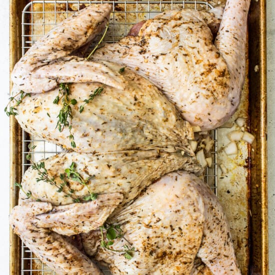 Roasted chicken on a baking sheet with herbs.
