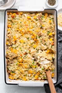 Chicken and vegetable casserole in a baking dish with a wooden spoon.