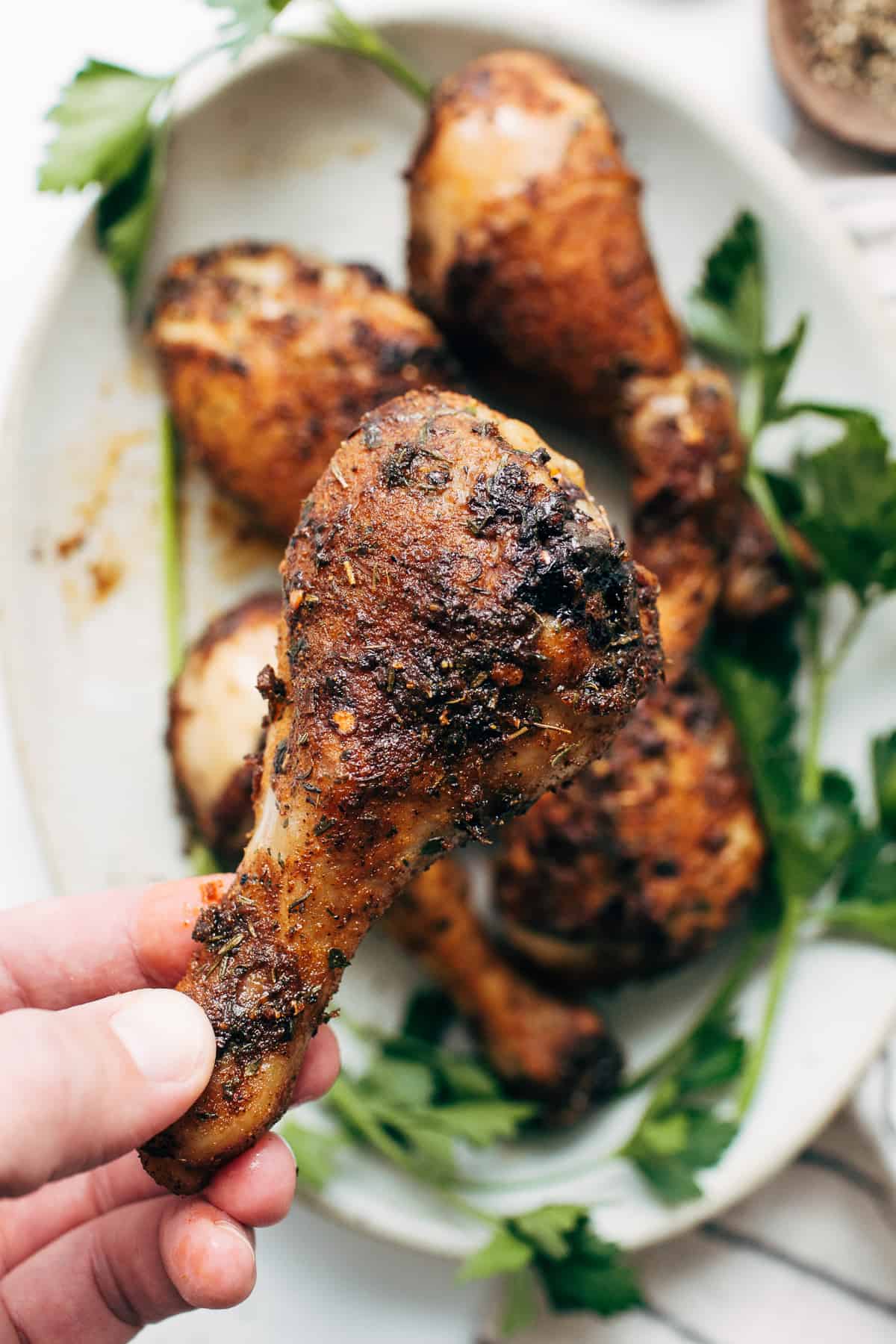 A hand holding a baked chicken leg.