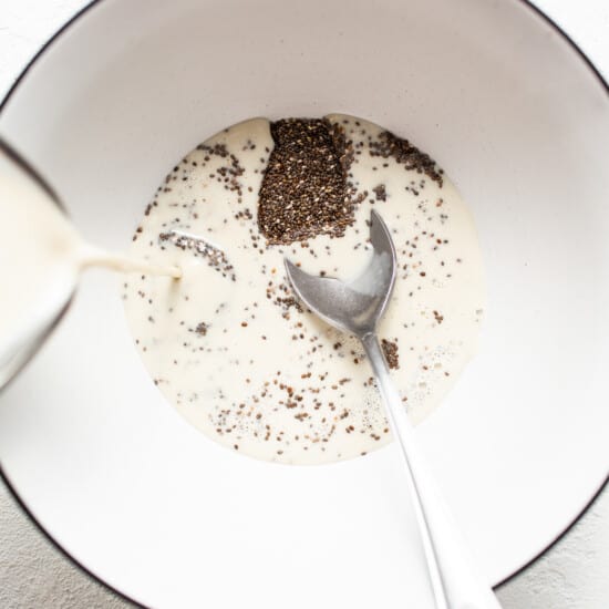 A spoon is pouring chia seeds into a bowl.