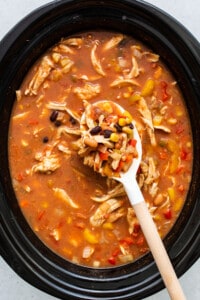 A bowl of mexican chicken soup with a wooden spoon.