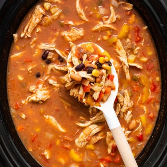 A bowl of mexican chicken soup with a wooden spoon.