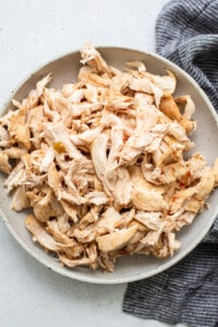 Shredded chicken in a bowl next to a napkin.