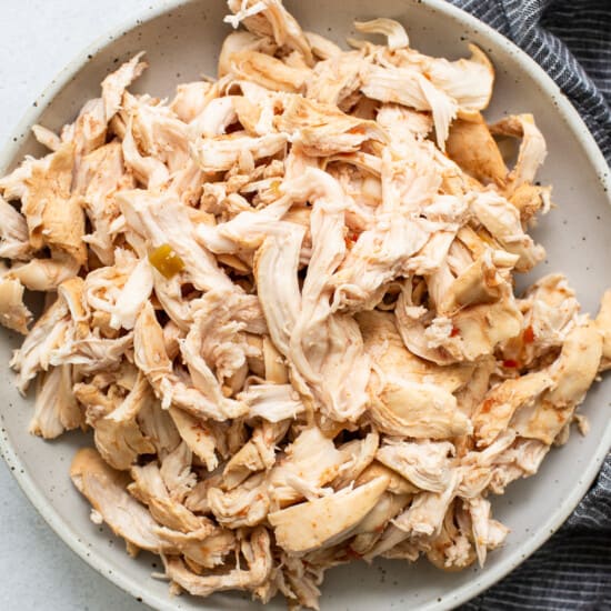 Shredded chicken in a bowl next to a napkin.