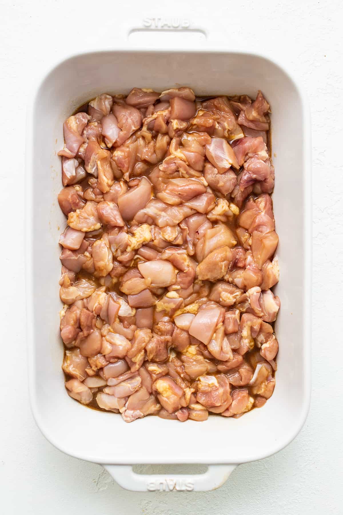 chicken marinating in casserole dish.