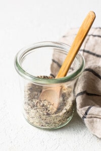 A glass jar with seeds and a wooden spoon.