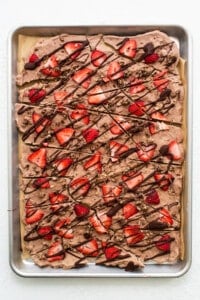 A sheet of chocolate covered strawberries on a baking sheet.