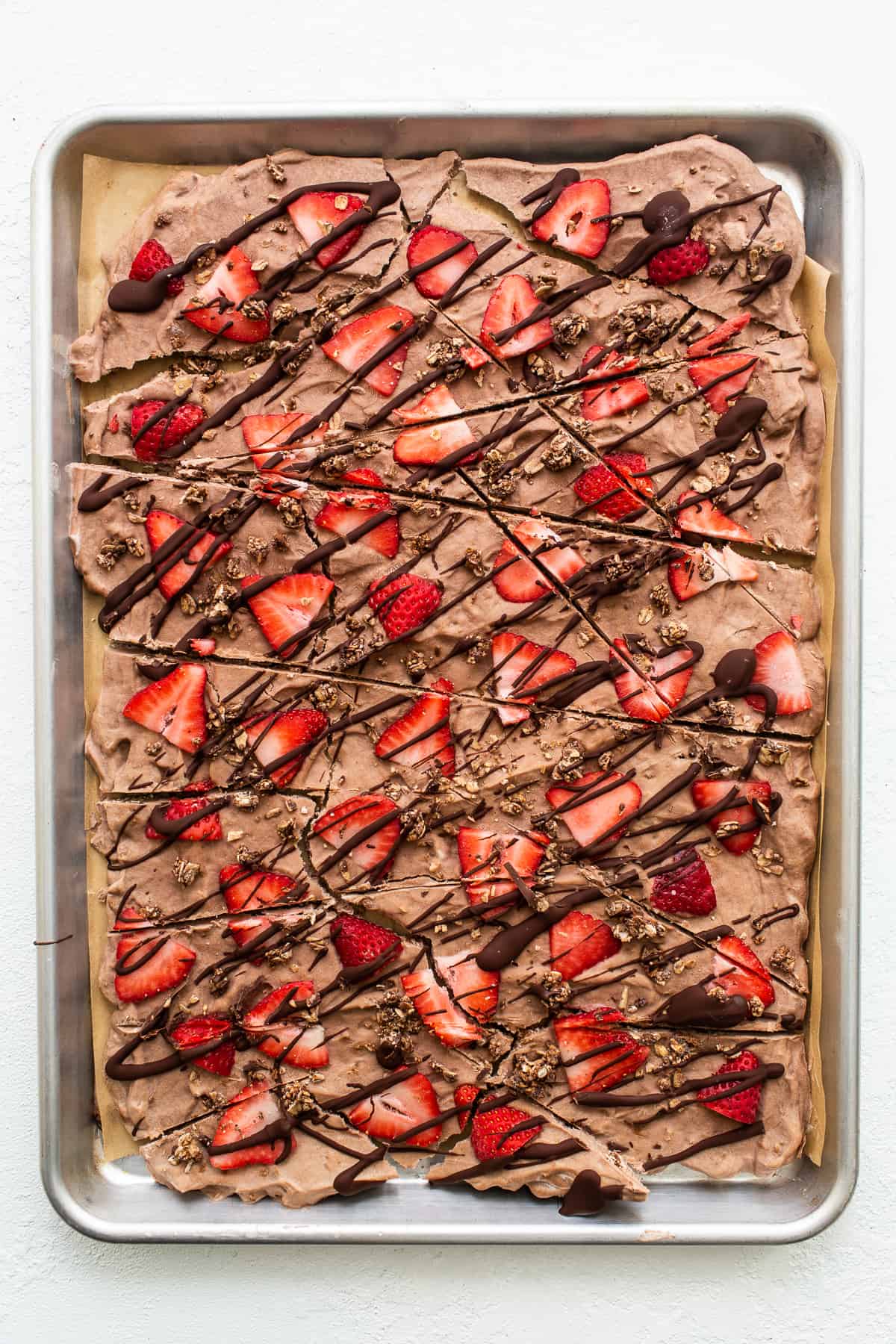 Frozen yogurt bark. topped with strawberries and drizzled with chocolate.