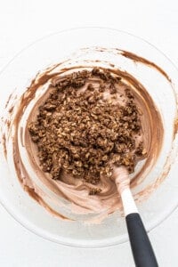 Chocolate granola in a bowl with a spatula.