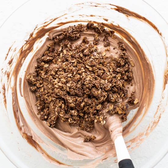 Chocolate granola in a bowl with a spatula.