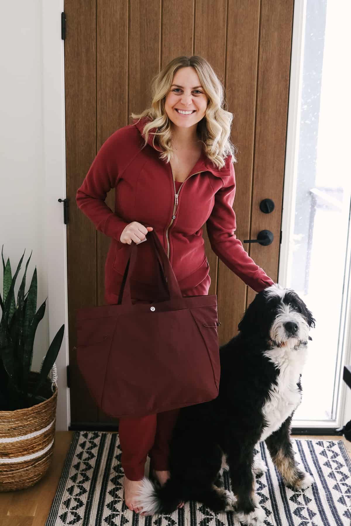 Woman carrying a bag standing next to a dog.